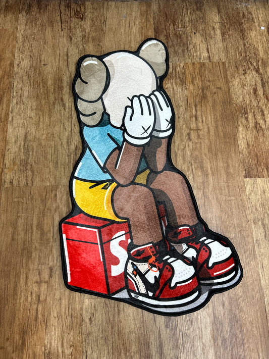 Kaws sitting down on box rug